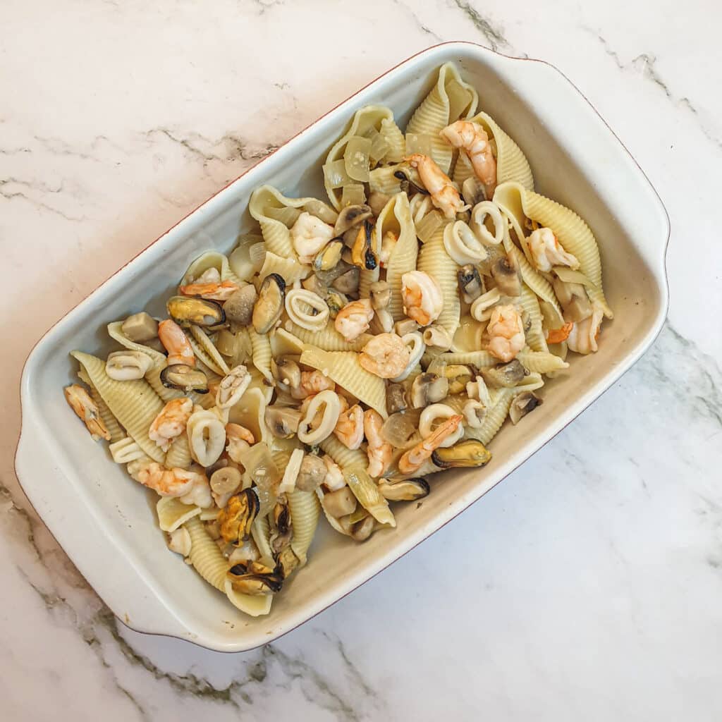 Pasta shells in a dish with seafood.