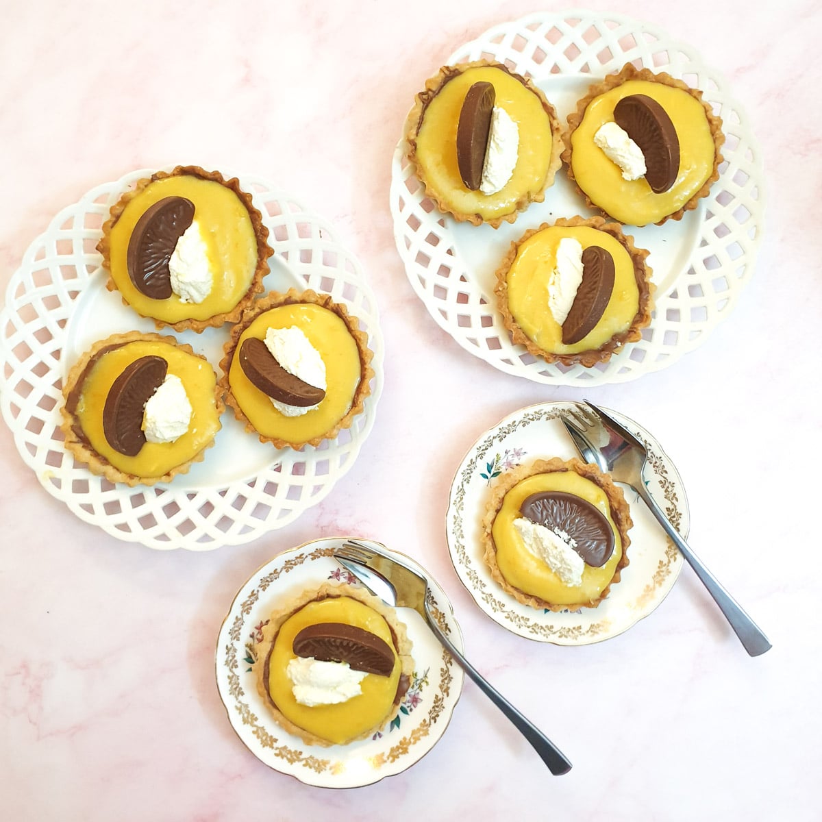 Overhead shot of 8 chocolate orange tarts on plates.