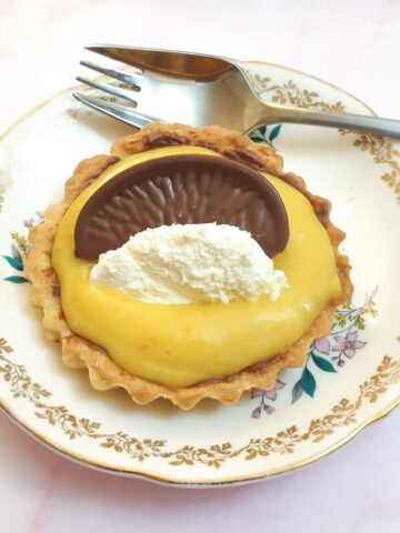 A chocolate orange tart on a small plate with a cake fork.