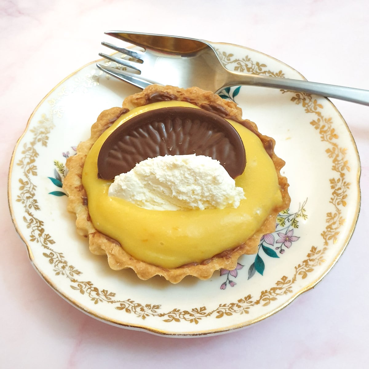 A chocolate orange tart on a small plate with a cake fork.