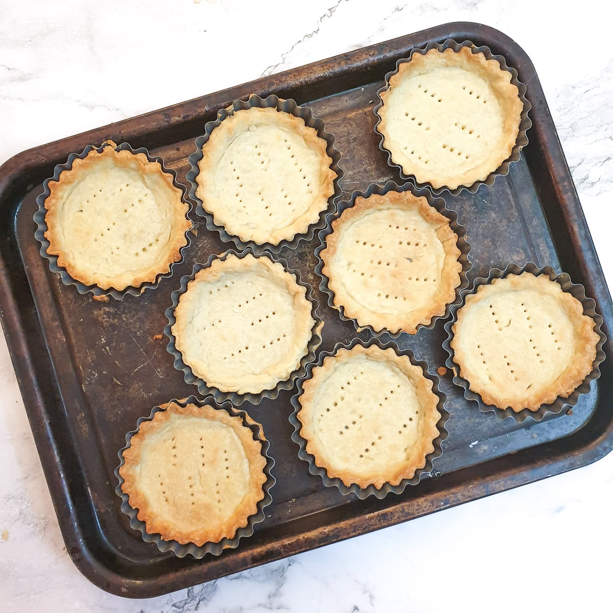 8 baked flan cases on a baking trayi.