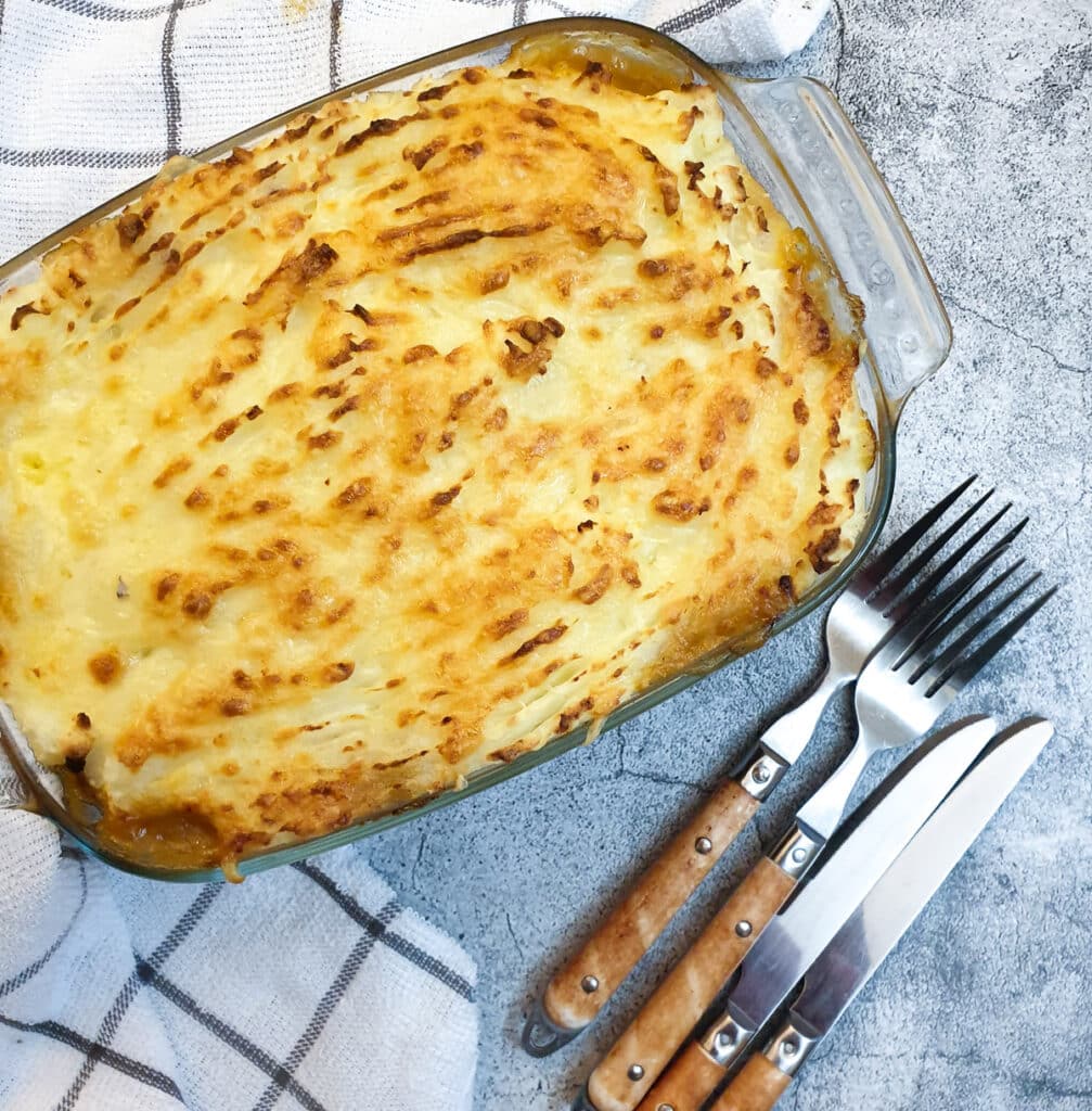 A dish of cottage pie covered with cheesy mashed potatoes.