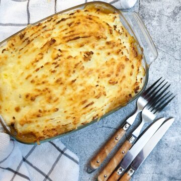 A dish of cottage pie covered with cheesy mashed potatoes.