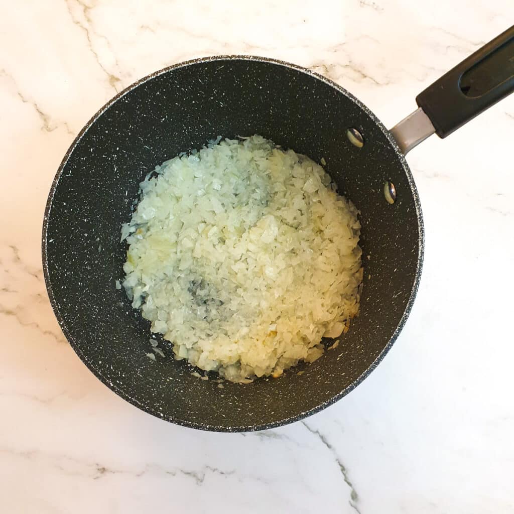 Finely chopped onions in a saucepan.