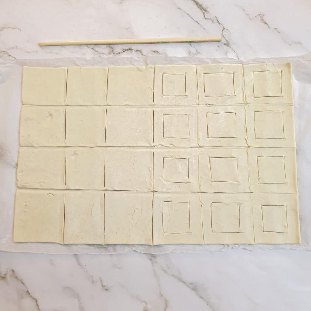 A sheet of puff pastry cut into squares ready to be assembled into vol-au-vents.