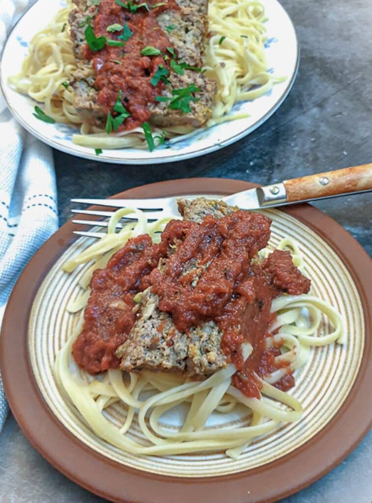 A plate of meatloaf and spaghetti covered in tomato sauce.