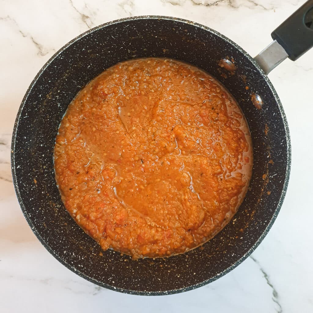 Tomato passata and spices added to the onions in a saucepan.