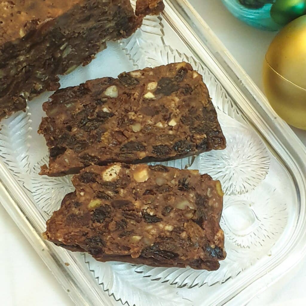 Two sices of no-bake Christmas cake on a glass tray, showing the texture of the cake. Two sices of no-bake Christmas cake on a glass tray, showing the texture of the cake.