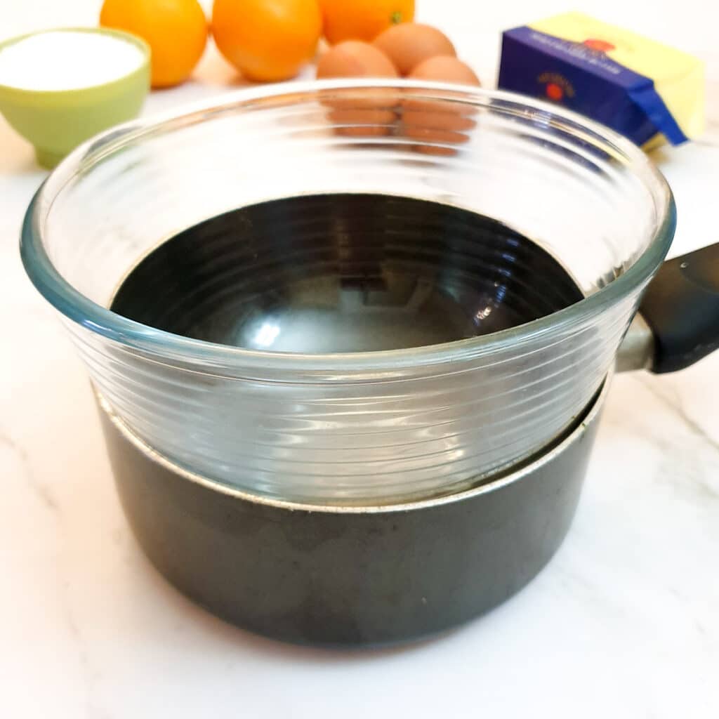 A glass bowl on top of a saucepan, showing how to improvise a double-boiler.