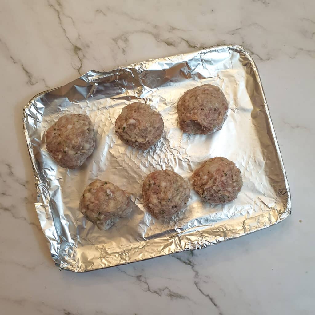 6 uncooked stuffing balls on an air-fryer oven shelf.