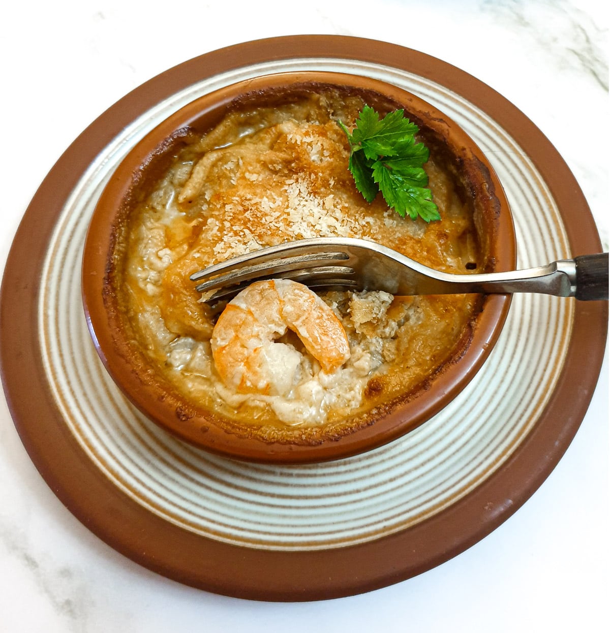 Close up of prawn and scallop au gratin with part of the topping removed to show the filling.