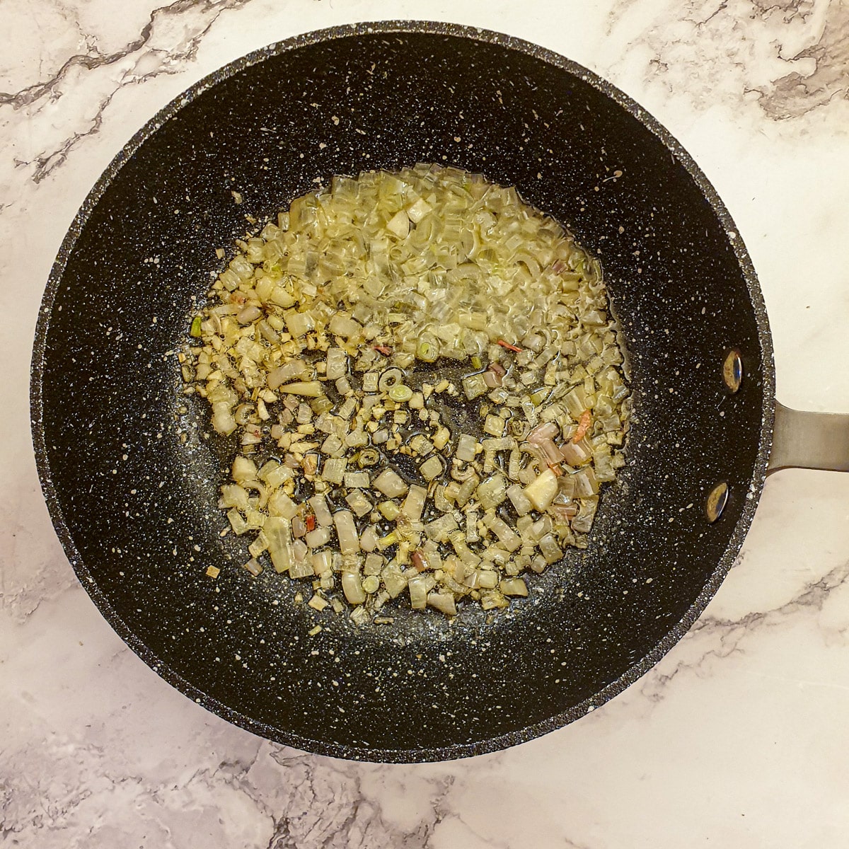 Finely chopped onions frying in butter in a saucepan.