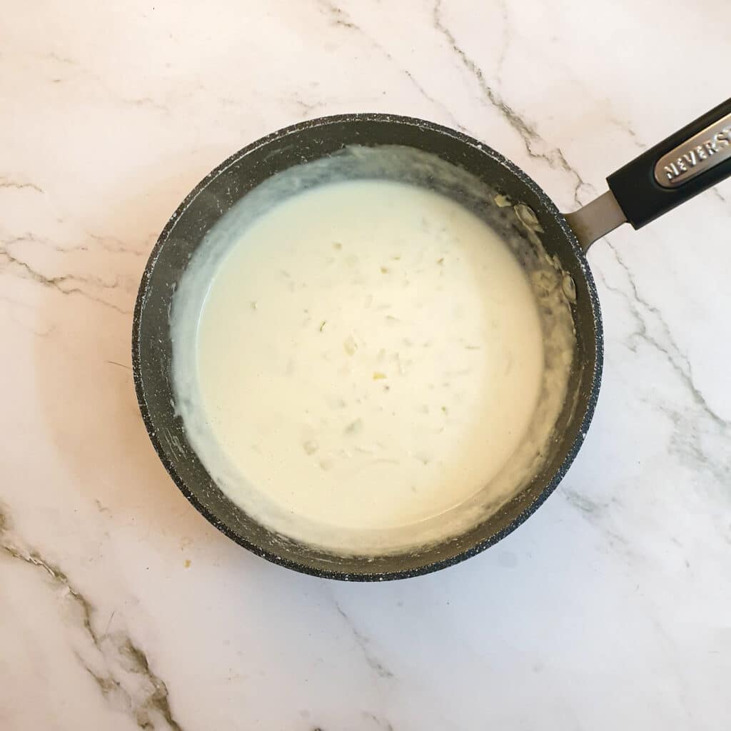 Milk and flour added to the onions in a saucepan. Milk and flour added to the onions in a saucepan.