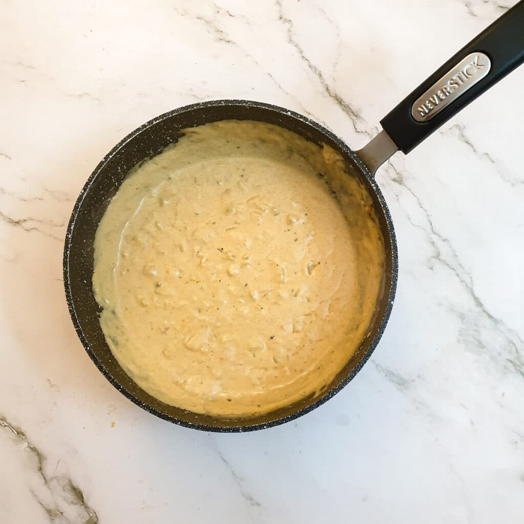 Cheese and paprika added to the onions and milk mixture in a saucepan.