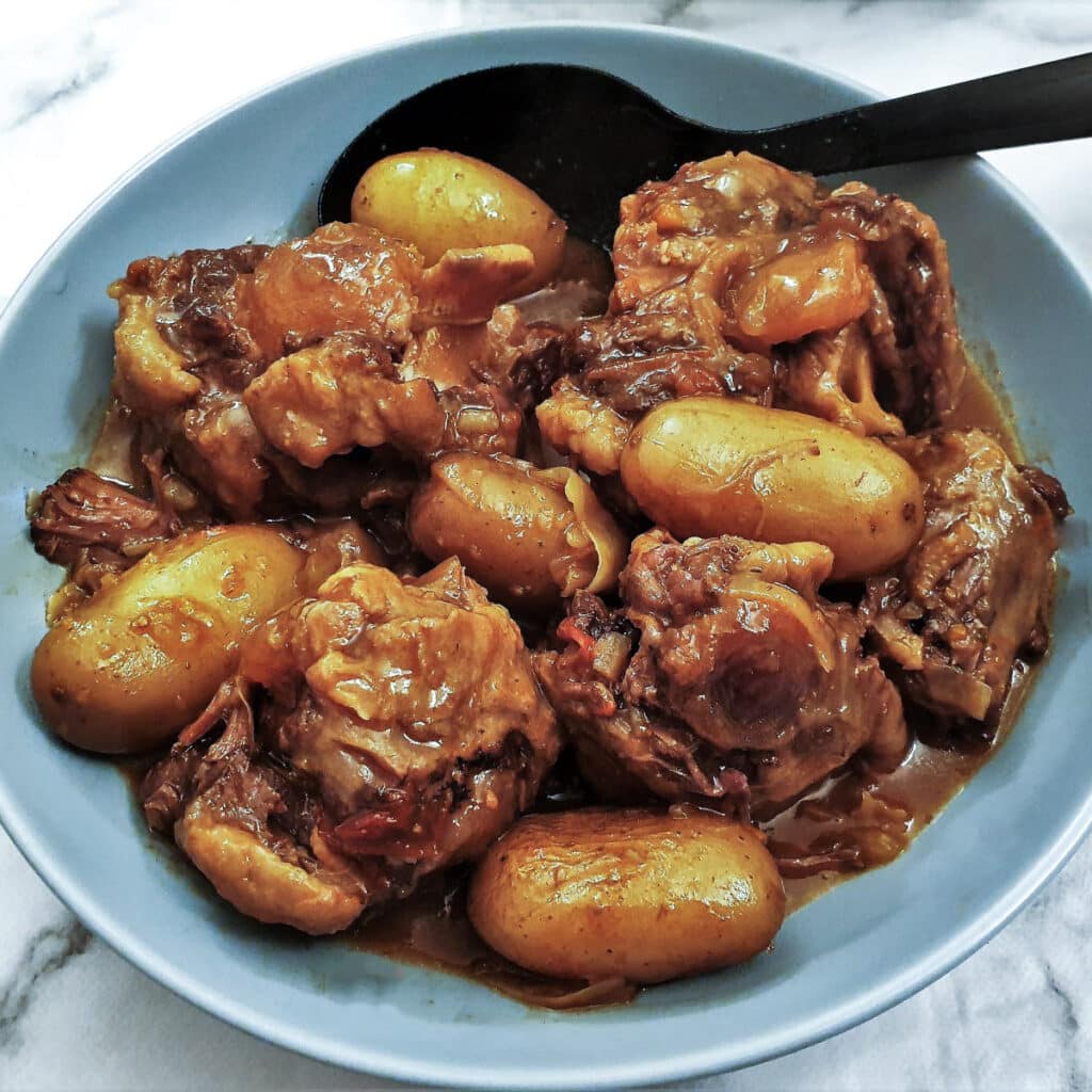 Overhead shot of slow cooker oxtail stew with a serving spoon.