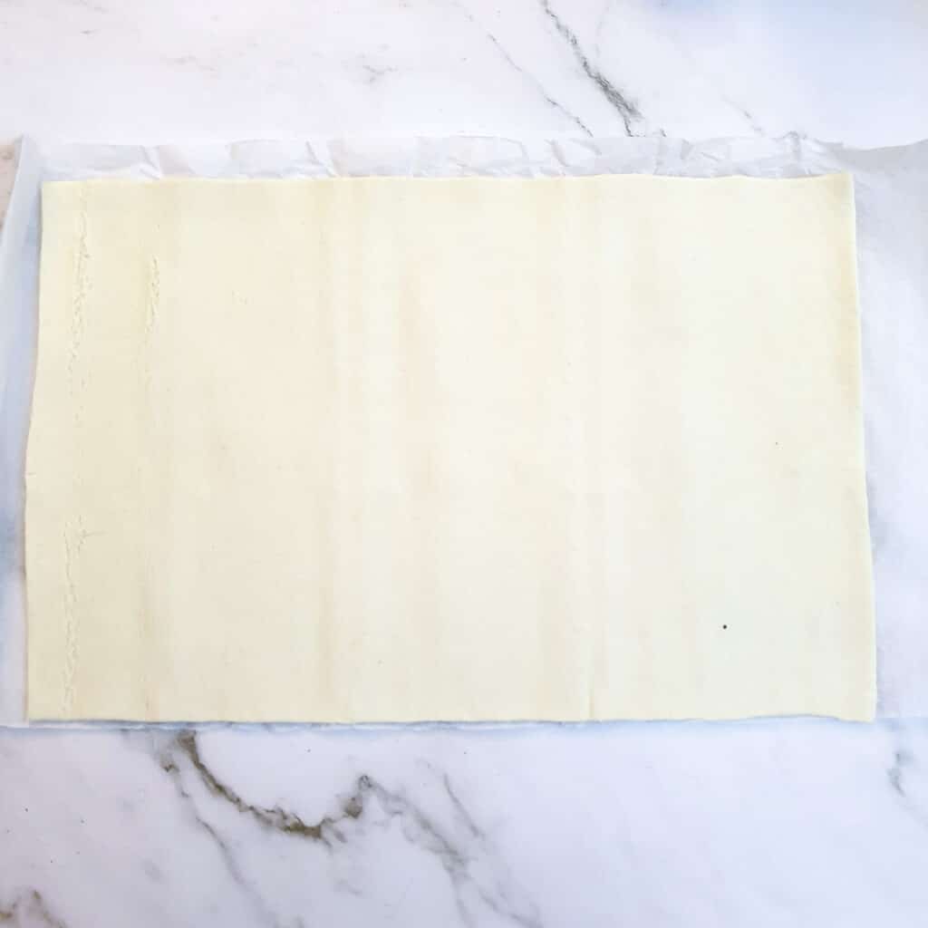 A sheet of puff pastry unrolled on a worksurface.