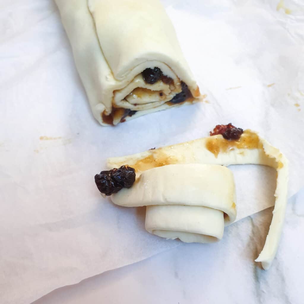 A roll of puff pastry and fruit mincemeat with the end trimmed off.