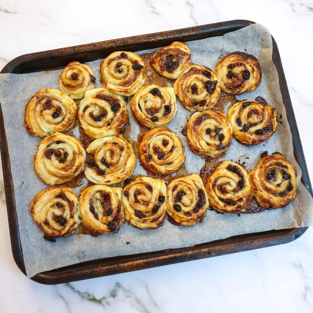 Baked Christmas fruit pinwheels on a baking tray.