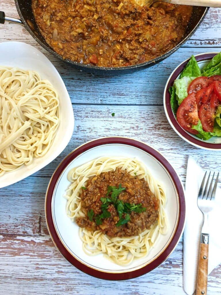 Overhead shot of a dish of linguine and bolognese sauce on a table.