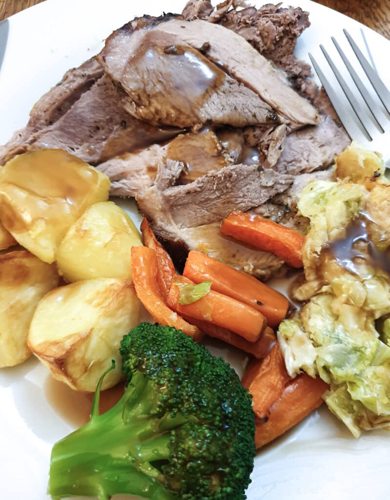 Slices of roast lamb on a plate with vegtables.