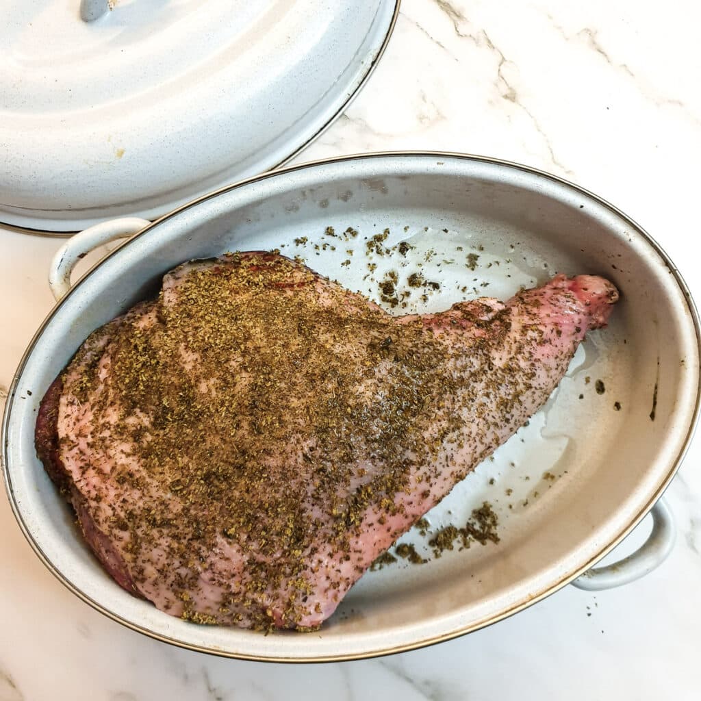 A leg of lamb which has been covered with dry mint rub before going into the oven.