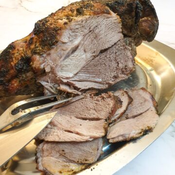 A roasted leg of lamb being carved into slices.