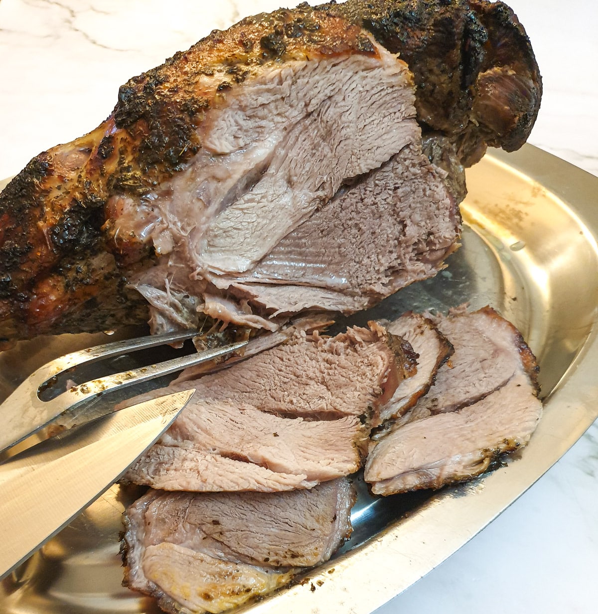 A roasted leg of lamb being carved into slices.