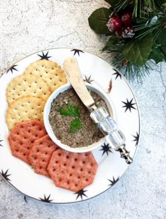 A dish of mushroom pate on a small plate with crackers.