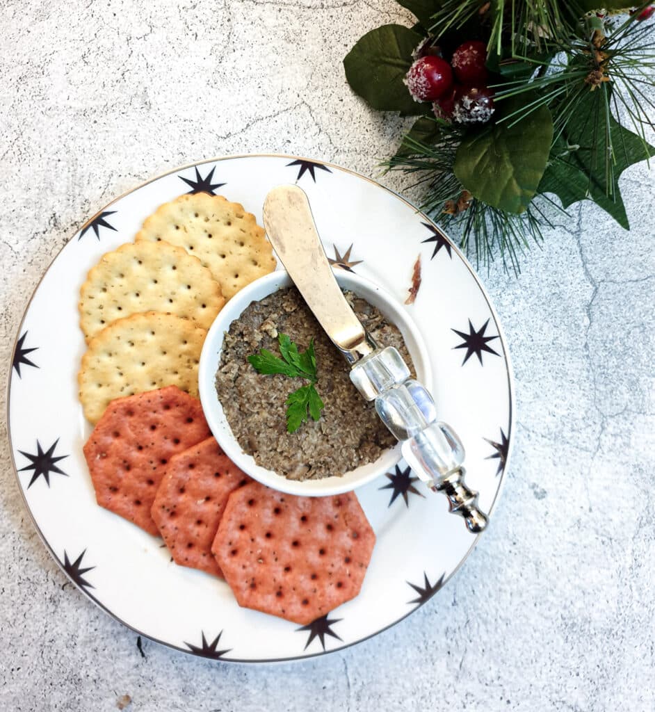 A dish of mushroom pate on a small plate with crackers.