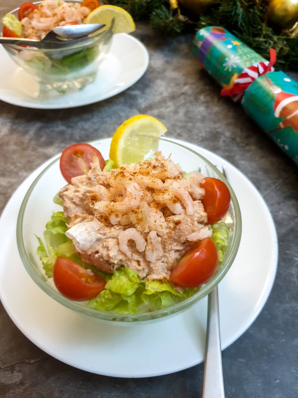 A dish of poor man's crayfish on a table next to a Christmas cracker.