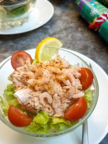 A dish of poor man's crayfish on a table next to a Christmas cracker.