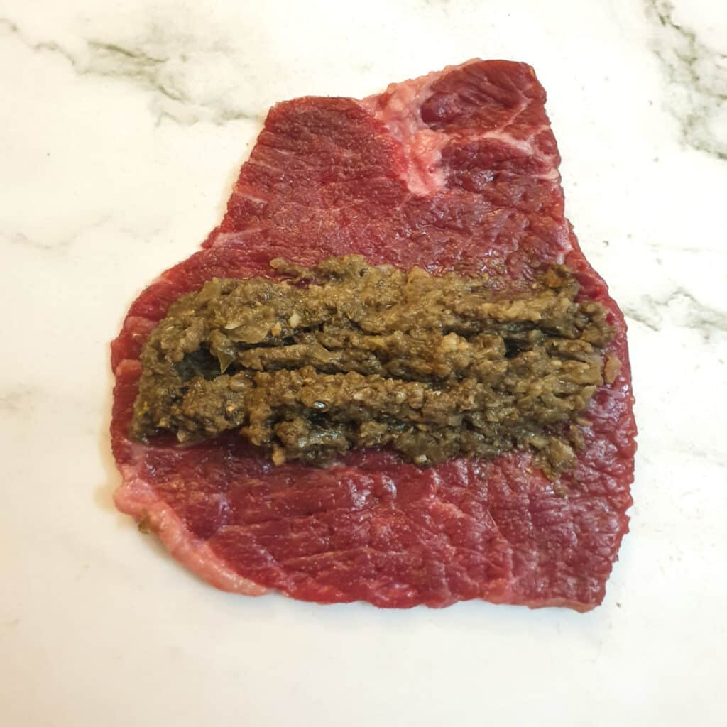 Mushroom mixture arranged in a log shape down the centre of a slice of steak.