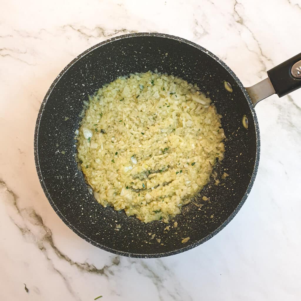 Chopped onions softening in butter in a saucepan.