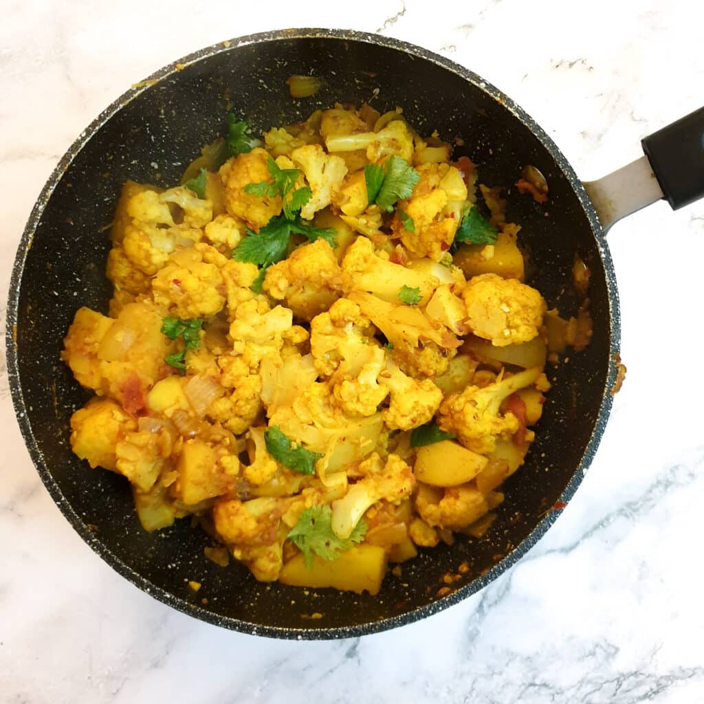 A frying pan holding the completed aloo gobi.