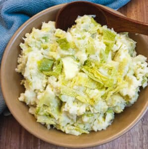 Irish colcannon in a brown serving dish with a brown wooden spoon.