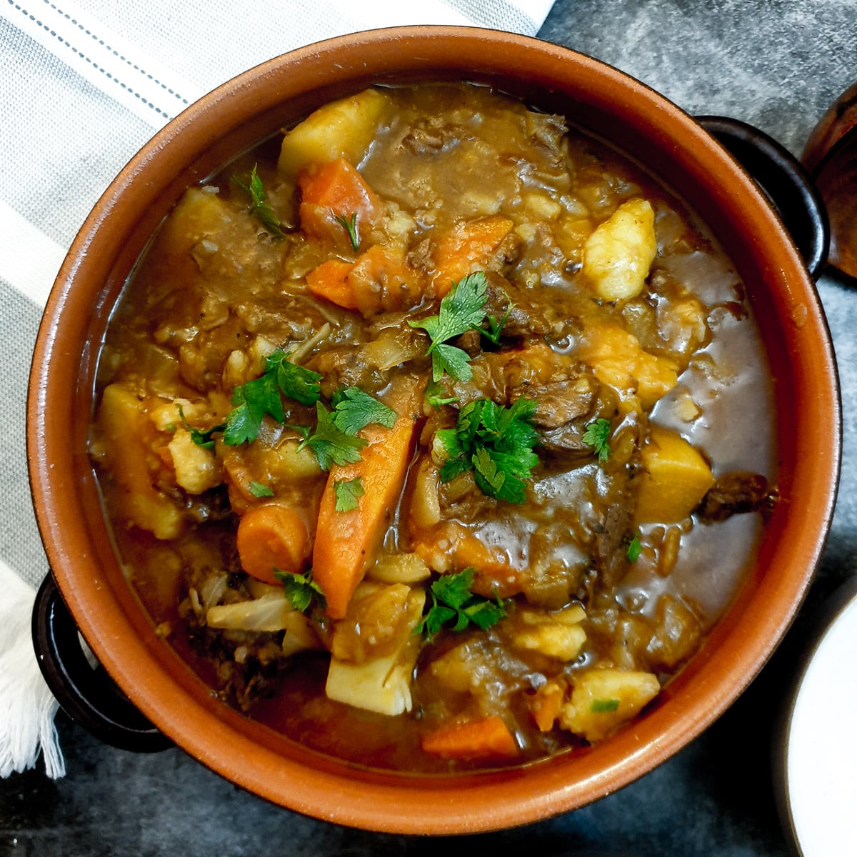 A dish of easy beef stew garnished with chopped parsley.