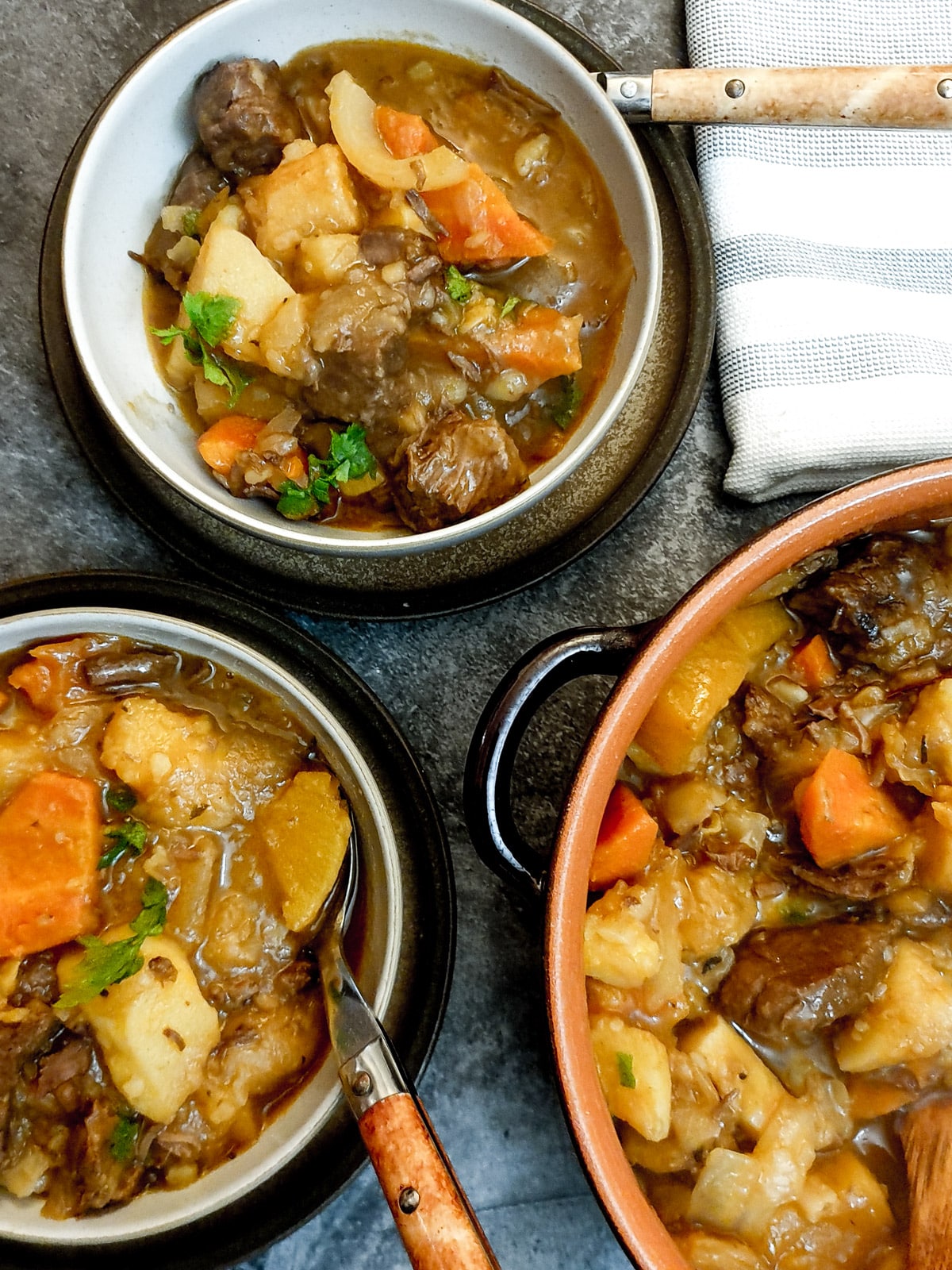 Overhead shot of beef stew in serving bowls with spoons.