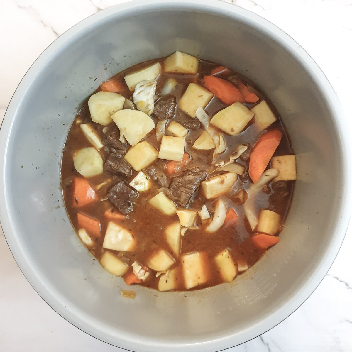 Potatoes and other root vegetables added to the stew.