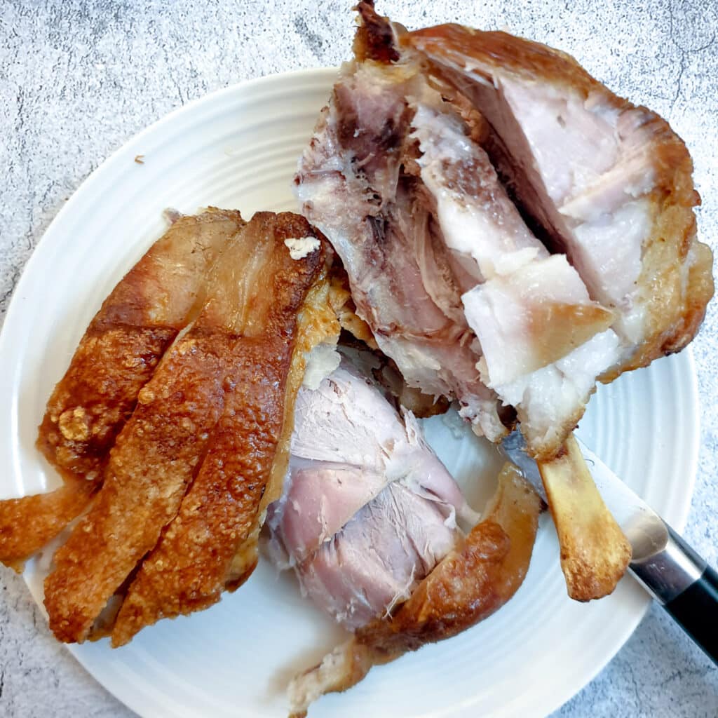 An eisbein cut in pieces to show the succulent meat below the crispy skin.