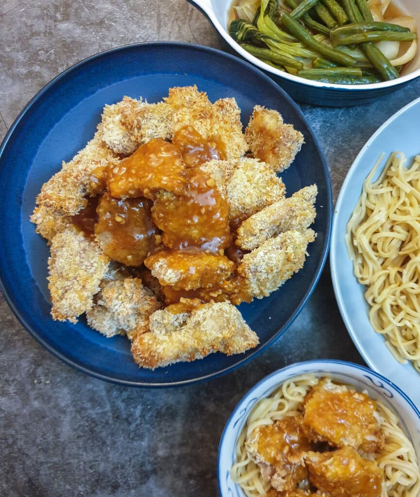 A dish of crispy chicken pieces coated in orange sauce.