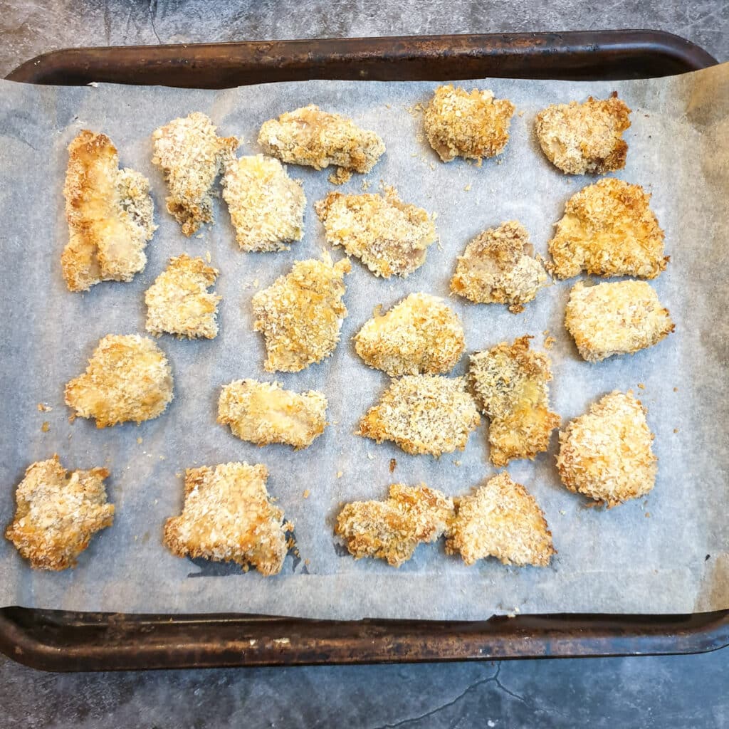 Pieces of browned crispy chicken on a baking tray.