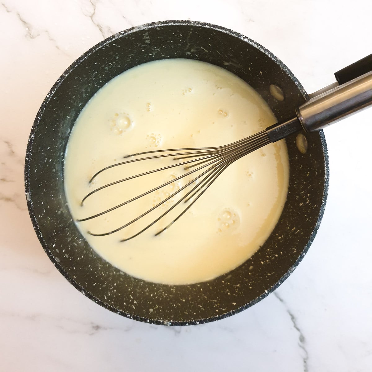 A saucepan containing custard.