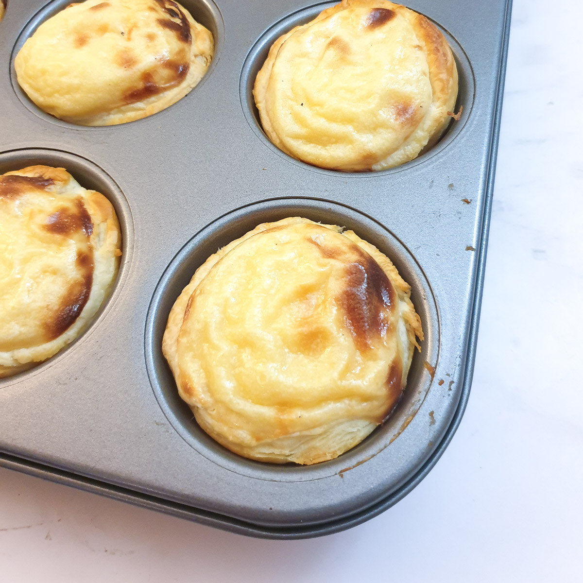 Close up of a Portuguese custard tart showing how the custard puffs up when the tart bakes.