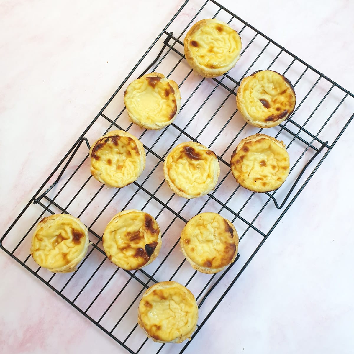 Portuguese custard tarts cooling on a wire rack.