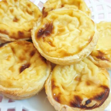 Close up of Portuguese custard tarts on a plate.