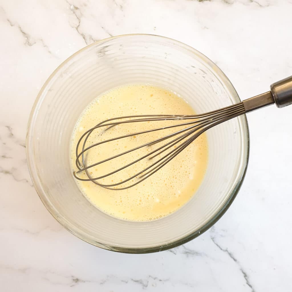 Egg yolks, milk and flour whisked together in a glass bowl.
