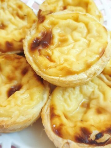 Close up of Portuguese custard tarts on a plate.