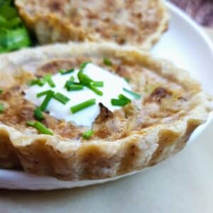 Closeup of a stilton and walnut tart garnished with creme fraiche and chopped chives.