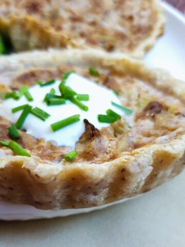 Closeup of a stilton and walnut tart garnished with creme fraiche and chopped chives.