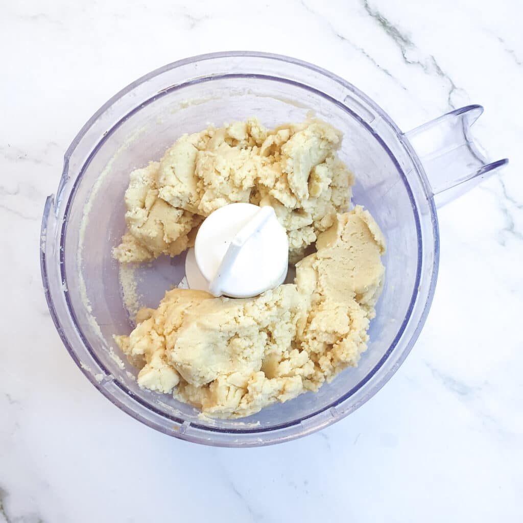 The cheesy pastry forming a ball in a food processor after the addition of water.